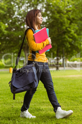 Female college student with books walking in park