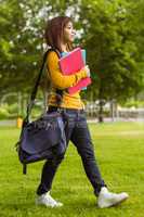 Female college student with books walking in park