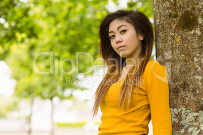 Beautiful young woman standing against tree