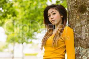 Beautiful young woman standing against tree
