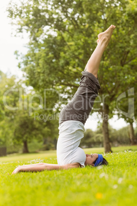 Concentrated brunette doing yoga on grass