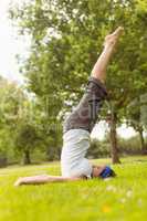 Concentrated brunette doing yoga on grass