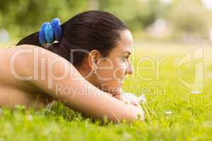Happy fit brunette lying on the grass