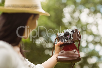 Brunette in straw hat taking a selfie with retro camera