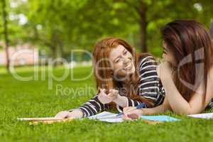 Cheerful female students with books in park
