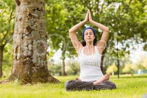 Brunette sitting in lotus pose on grass