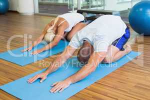 Couple in bending posture at fitness studio