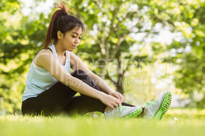 Healthy woman relaxing in park as she ties shoelace