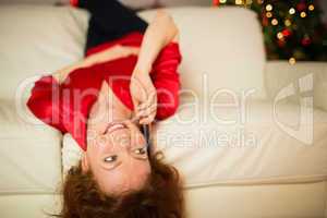 Happy redhead lying on the couch phoning