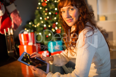 Redhead woman sitting on floor using tablet at christmas