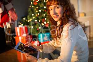 Redhead woman sitting on floor using tablet at christmas