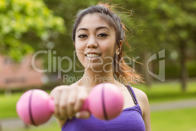 Healthy woman lifting dumbbell in park