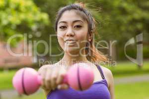 Healthy woman lifting dumbbell in park