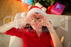 Smiling redhead doing heart sign at christmas