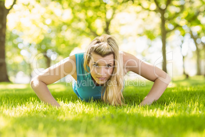 Fit blonde doing push ups in the park