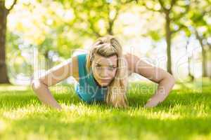 Fit blonde doing push ups in the park