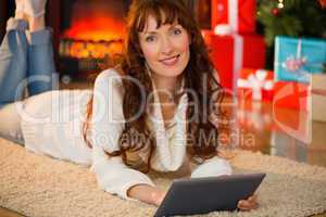 Redhead woman lying on floor using tablet at christmas