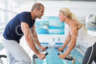 Side view of couple working on exercise bikes at gym