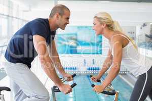 Side view of couple working on exercise bikes at gym