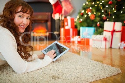 Redhead woman lying on floor using tablet at christmas