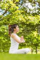 Healthy woman sitting with joined hands at park