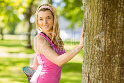 Fit blonde stretching against a tree