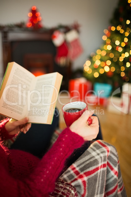 Woman in jumper reading and drinking coffee