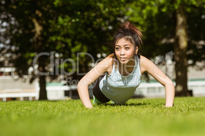 Healthy woman doing push ups in park