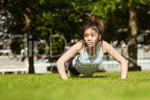 Healthy woman doing push ups in park
