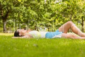 Cheerful fit brunette lying and relaxing on the grass