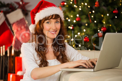 Redhead in santa hat using laptop on the couch