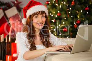 Redhead in santa hat using laptop on the couch