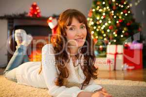 Smiling redhead woman lying on floor at christmas