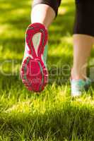 Woman in running shoes jogging on grass