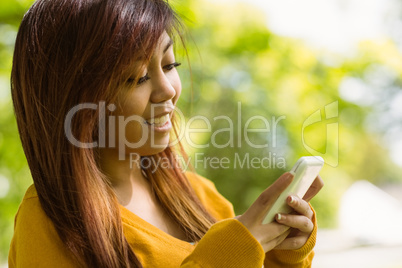 Beautiful woman text messaging in park