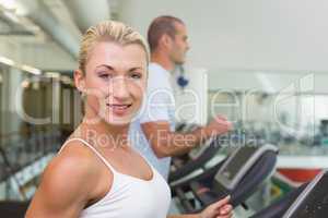 Fit couple running on treadmills at gym