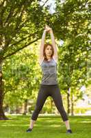 Pretty athletic redhead stretching in park