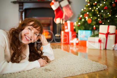 Smiling redhead woman lying on floor at christmas