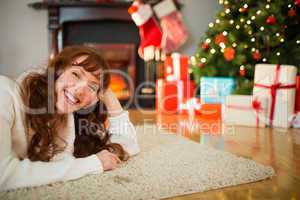 Smiling redhead woman lying on floor at christmas