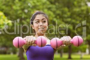 Healthy woman lifting dumbbells in park