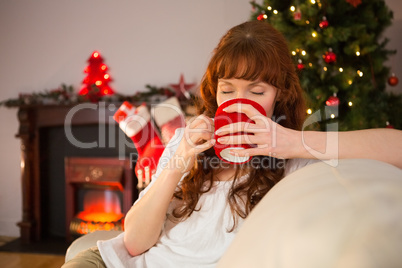 Pretty redhead sitting on couch drinking hot chocolate