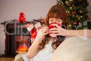 Pretty redhead sitting on couch drinking hot chocolate