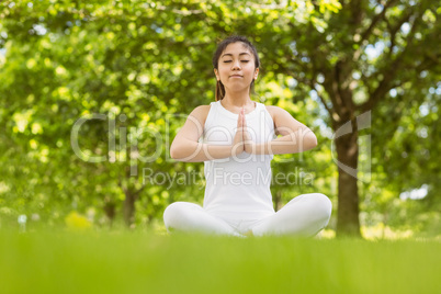 Healthy woman sitting with joined hands at park