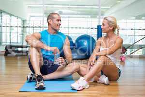 Fit couple sitting on floor at fitness club