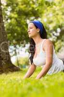 Peaceful brunette doing yoga on grass
