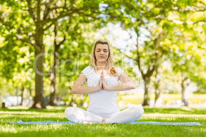 Fit blonde sitting in lotus pose in the park