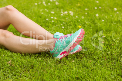 Woman in running shoes lying on grass