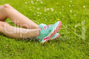 Woman in running shoes lying on grass