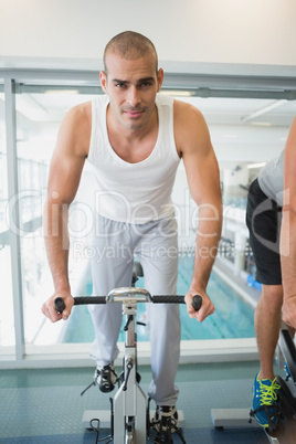 Handsome man working out on exercise bike at gym