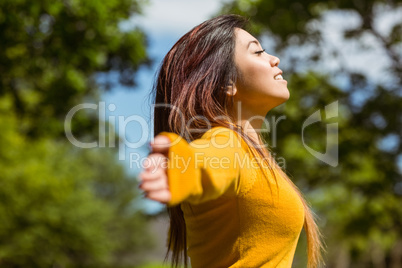 Beautiful woman with arms outstretched in park